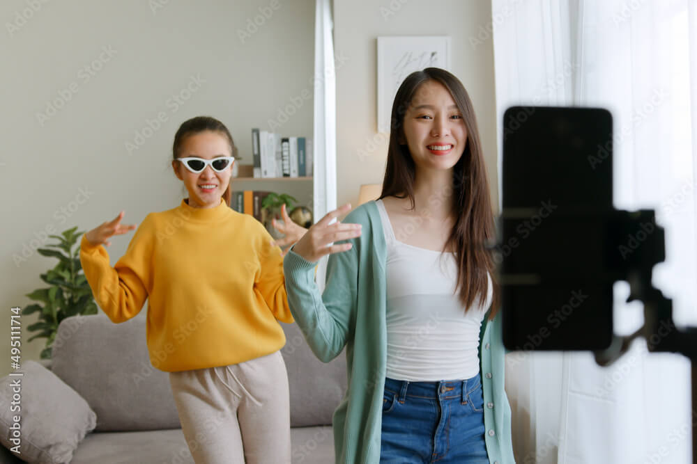 Two women creating a dancing video on their mobile phone 1